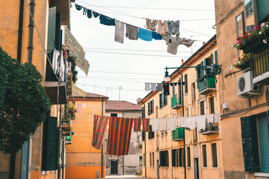 Traditional Venetian scene of fresh laundry hanging on clotheslines between historic residential buildings above narrow streets and courtyards in Venice, Italy.