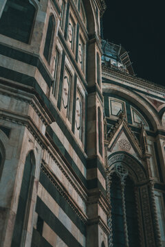 Low-angle night shot of the intricate polychrome marble facade of the Florence Cathedral (Duomo), showcasing Gothic architectural details.