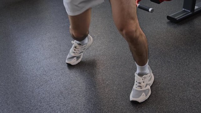Curly haired Asian man having boxing workout in gym. He practicing punches and improving footwork