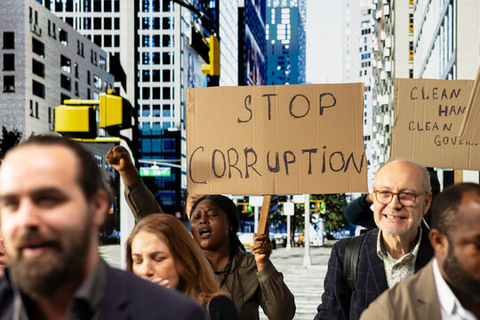 Warring crowd of activists chanting against corruption and political misconduct, holding banners and posters asking to stop corruption, wanting public accountability and democracy.