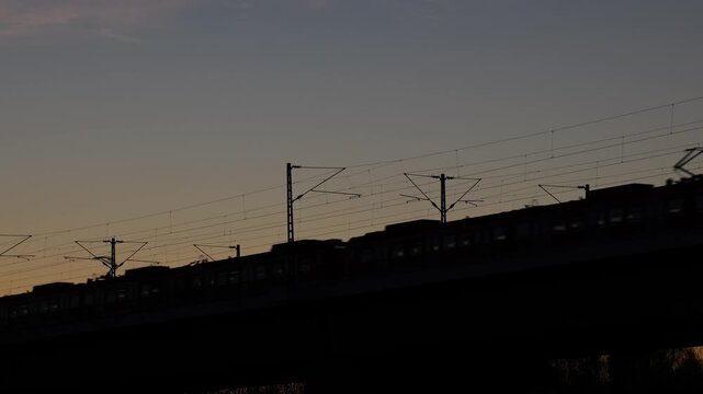High speed passenger train silhouette on railway bridge at sunset with copy space, minimal transport scene in Europe