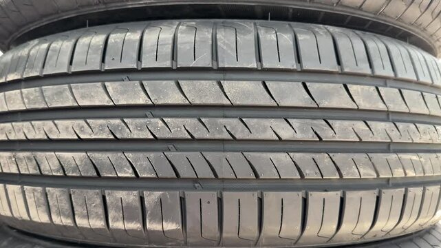 Stacked summer tires at pickup point, closeup of new tread patterns and rubber texture, retail inventory on pallets in outdoor.