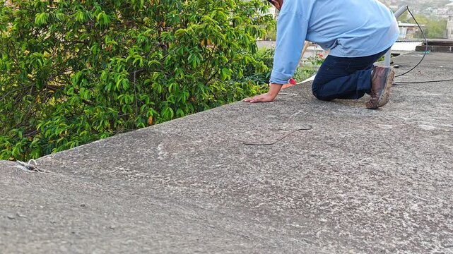 Man kneeling while cleaning roof gutter drainage