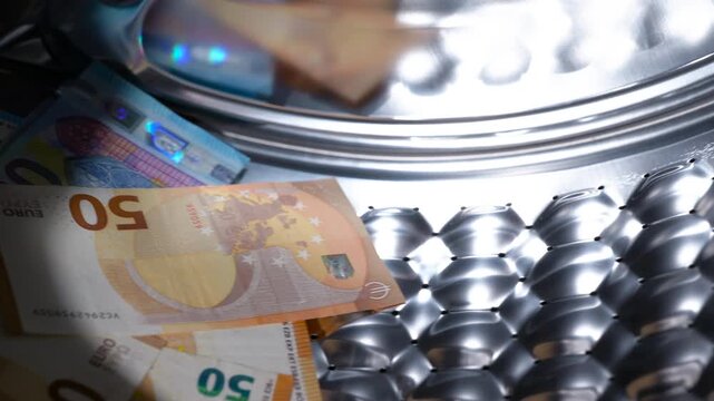Euro banknotes spinning in a washing machine drum. Illegal cash laundering concept showing a pile of euro banknotes tumbling inside the spinning drum of a washing machine, symbolizing corruption