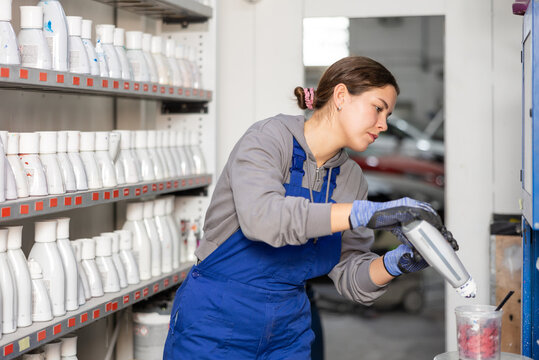 Girl colorist selects paint color by mixing different paint colors for subsequent painting of car in a car service center