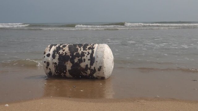Oil pollution of sea, coast. Floating objects (flotsam, trawl float) are covered with fuel oil and bring toxin to other parts of sea, secondary pollution. Sandy beach attacked by fuel. South China Sea