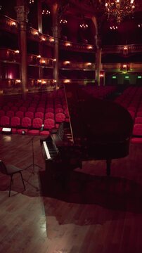 A lone pianist plays on stage in an ornate opera house, surrounded by a sea of empty red seats. The warm glow of the lights creates an inviting atmosphere reflecting the beauty of music.