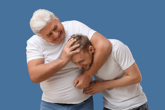 Senior man messing around with his son on blue background