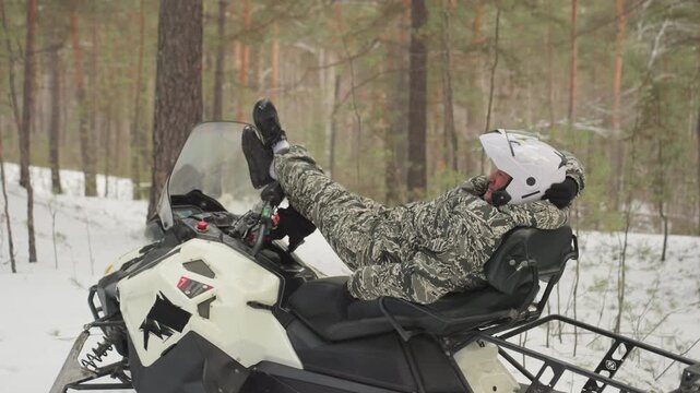 Sled rider playing. Reclining person on sled in winter landscape. Relaxed rider on sled amidst snowfall in frosty woods. Person lounging on sled in snowy forest with snow falling gently around