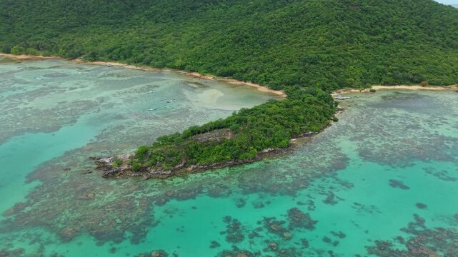 Aerial view of Annora Beach's vivid turquoise waters meeting lush green shores and a small island, Karimunjawa, Central Java, Indonesia.