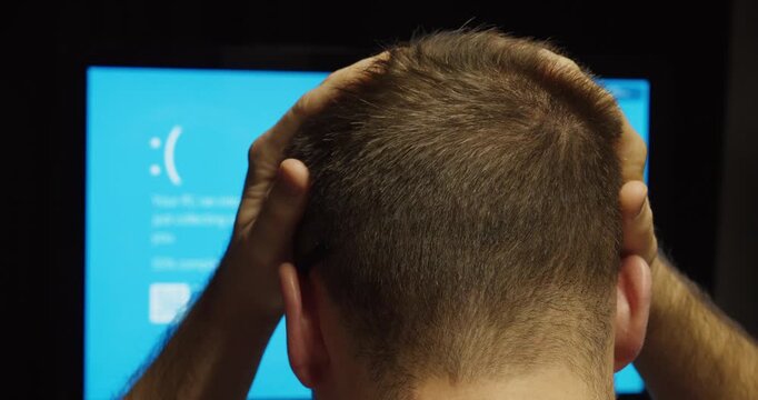Man holding his head in frustration after computer crash, representing stress and system failure.