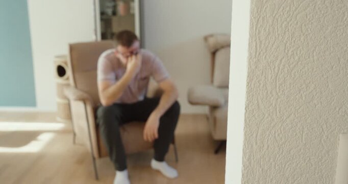 Soft focus shot of a sad man sitting alone in a chair with a blurred foreground and bokeh effect, showing depression, loneliness, emotional distress, mental health struggles, and personal reflection.