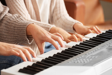Obraz premium Female music teacher giving synthesizer lesson to little girl at home, closeup