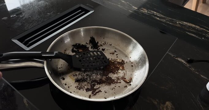 Burnt Food in Frying Pan Being Scraped &ndash; Cooking Mistake and Failure Concept