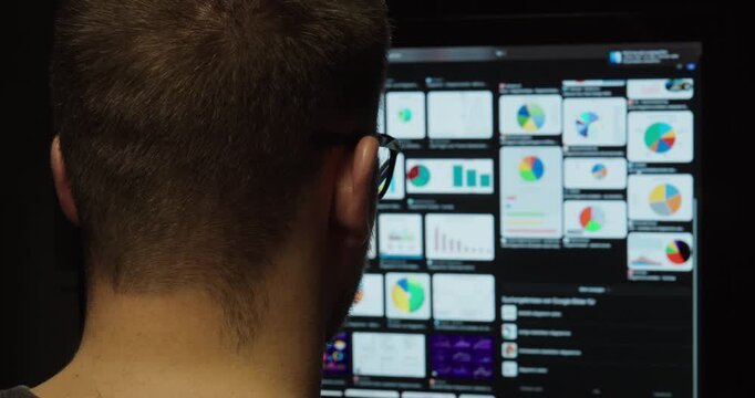 Data Scientist Reviewing Complex Analytics Dashboard in Dark Office Environment