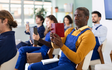 Obraz premium Male worker take picture with mobile phone or photograph QR code on bulletin board in a classroom