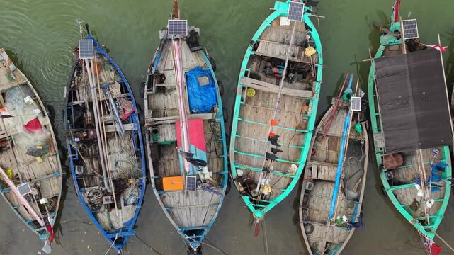 Aerial view of fishing boats docked at Jepara Floating Fish Market, showcasing textures and tones, and the contrast between the boats and the water, Jepara, Central Java, Indonesia.