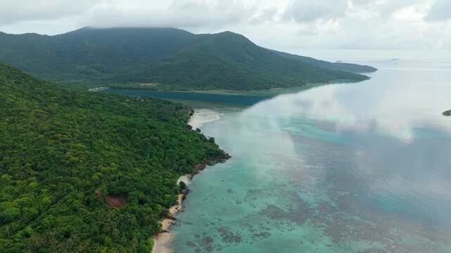 Aerial view of Karina Beach where turquoise waters meet lush green forests in a vibrant display of nature's beauty, Karimunjawa, Central Java, Indonesia.