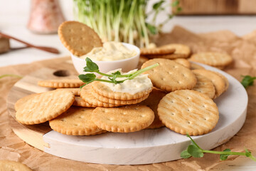 Tasty crackers with bowl of sauce and fresh micro green on white background