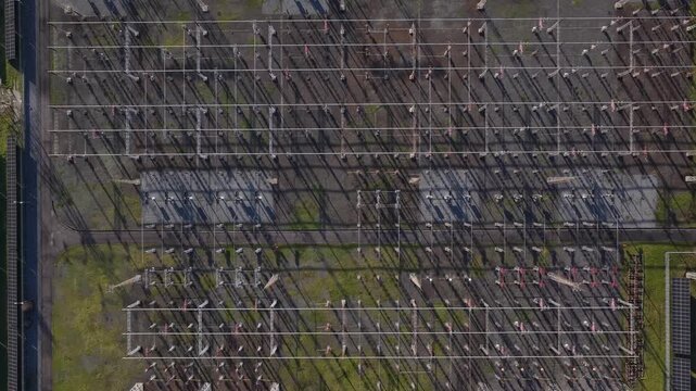 Aerial view of a sprawling electrical substation, the gridlines casting long shadows across the landscape, a stark contrast of industrial gray and green, Custoias, Porto, Portugal.