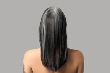 Fototapeta premium Young woman with graying hair on color background, back view