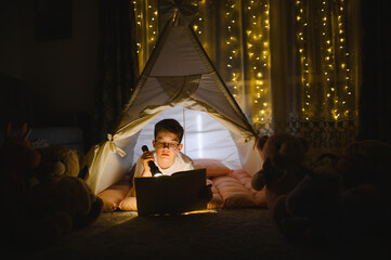 Obraz premium Boy reading story in tent during bedtime