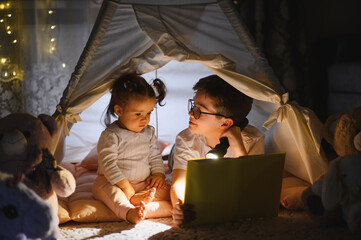 Obraz premium Brother reading bedtime story to sister in tent