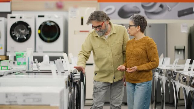 Mature couple choosing washing machine in appliance store