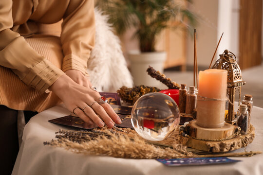 Female fortune teller reading tarot cards on table in room