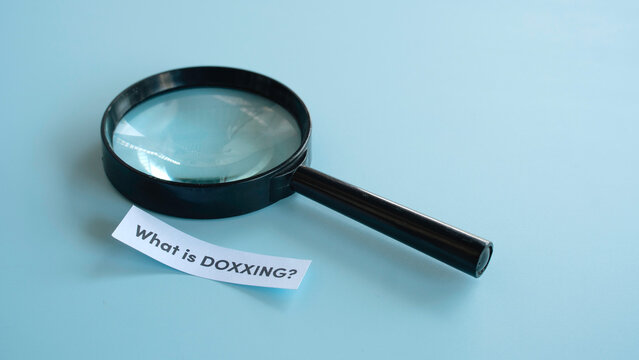 Black magnifying glass on blue background with what is doxxing text