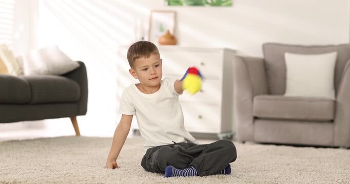 Little boy playing with handmade toy rocket on floor indoors