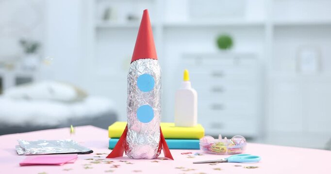 Star shaped confetti falling over handmade rocket on table indoors