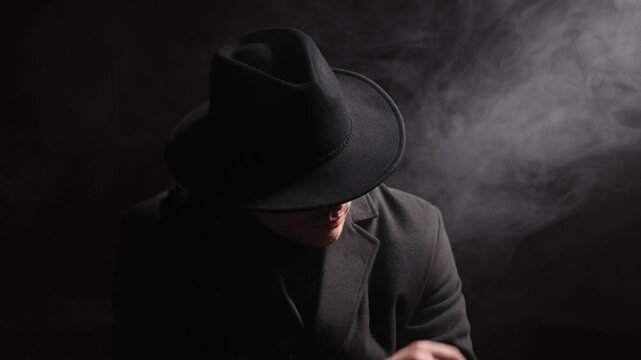 Man wearing stylish hat on black background with smoke