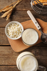 Naklejka premium Glass of fresh kefir with wheat and bowl of cottage cheese on wooden background