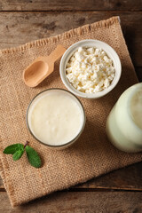Naklejka premium Glass of fresh kefir with mint and bowl of cottage cheese on wooden background