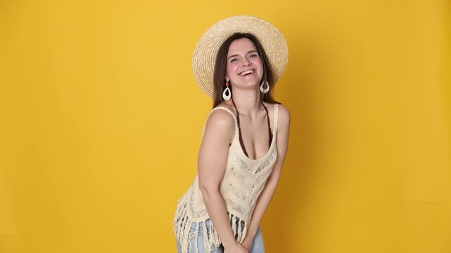 Beautiful woman in stylish beachwear posing on yellow background