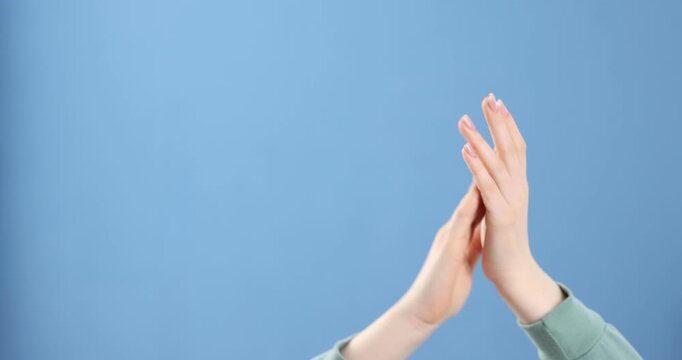 Woman clapping hands on blue background, closeup