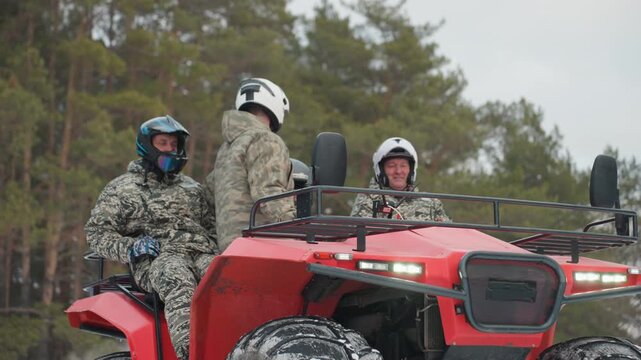 Three riders power red atv across snow with pine forest backdrop, hightraction tires carving snow, frontal motion shot captures speed, momentum and team coordination, winter landscape and vehicle