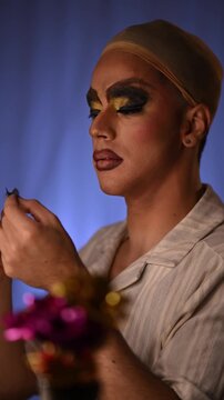 Drag queen applying false eyelashes during makeup routine in front of a mirror preparing for a show in the dressing room