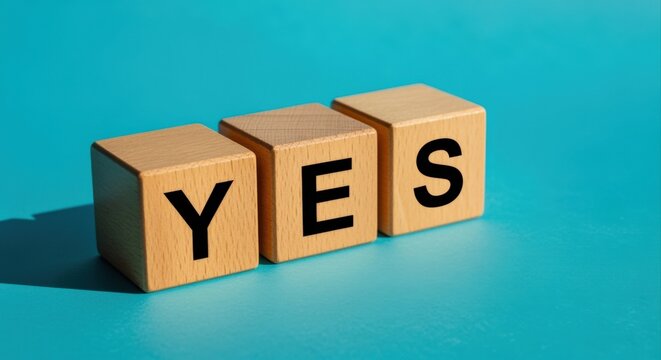 Three wooden cubes spelling out the word YES, symbolizing agreement and positive confirmation against a bright blue background.