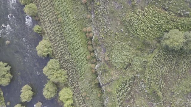 Drone with camera pointing down flies diagonally over Senqunyane River on a late afternoon in the mountains of Lesotho