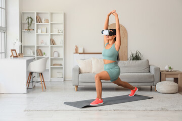 Obraz premium Sporty African-American woman in VR glasses training on mat at home