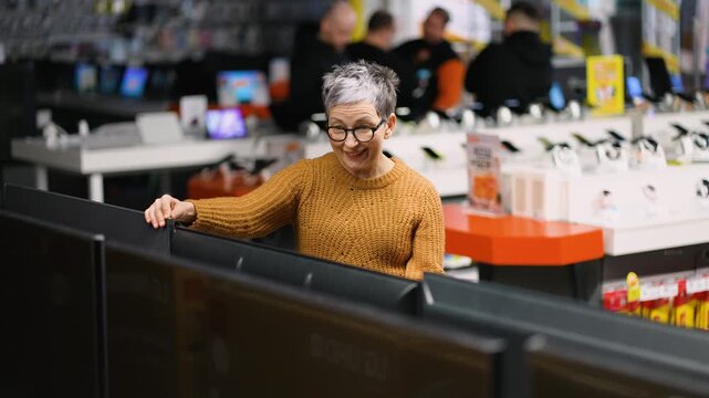 Mature woman choosing new tv at electronics store on Black Friday