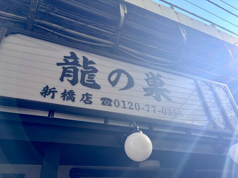Ryu no Su restaurant storefront sign in Shinbashi district featuring traditional Japanese calligraphy and contact information against a blue sky - Tokyo, Japan, October 15, 2024