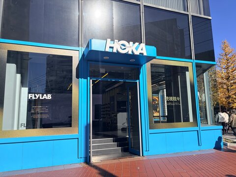 HOKA Marunouchi flagship storefront with signature blue facade and FLYLAB branding on display windows during a sunny autumn day - Tokyo, Japan, November 15, 2024