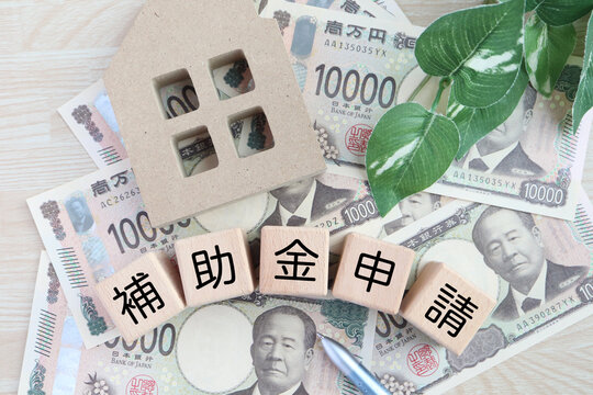 補助金申請と家計管理・日本円紙幣と木製ブロック「補助金申請」