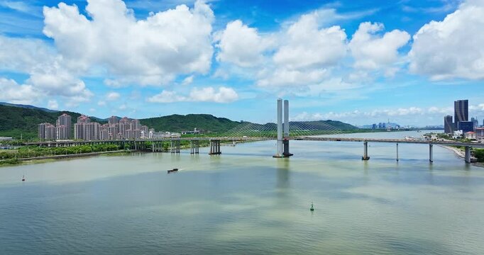 Aerial view of a modern cable-stayed bridge spanning the river, connecting city districts in Zhuhai, China.