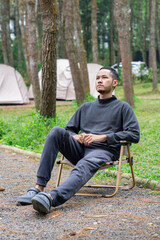 Obraz premium A man sitting relaxing on camp site in the forest