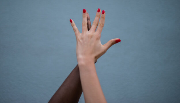 Manos entrelazadas de diferentes tonos de piel simbolizando diversidad, inclusi&oacute;n y conexi&oacute;n humana sobre fondo neutro