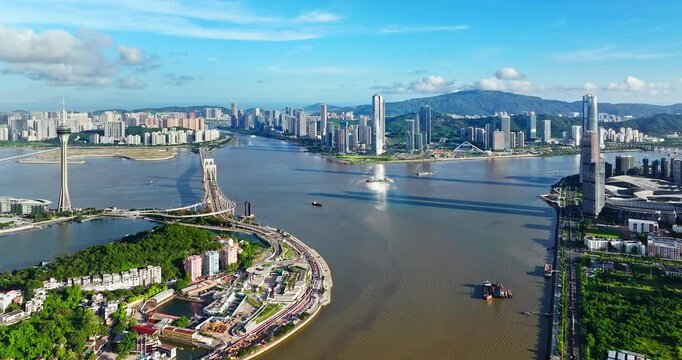Drone view of Zhuhai city skyline and Macau Tower across the water, coastal city infrastructure and bridges connecting urban districts, China.